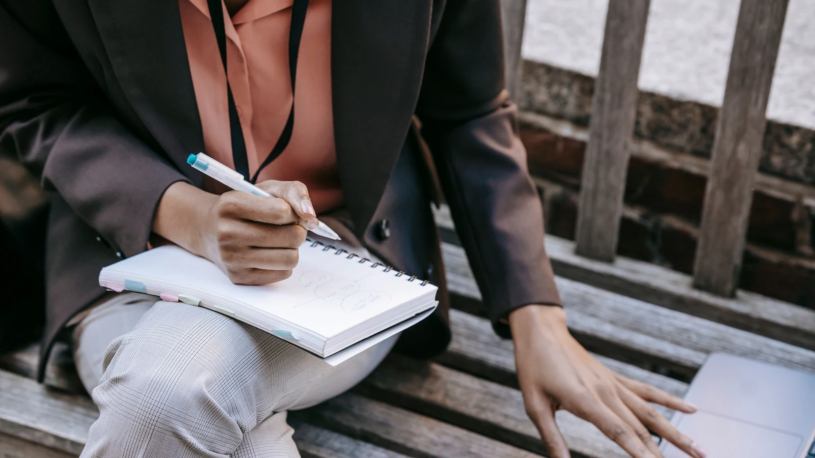 Stratège de contenu prenant des notes dans un carnet à l'extérieur